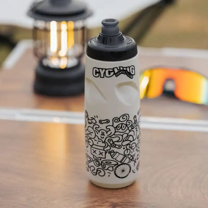 Hvit Santic sykkelflaske med svarte illustrasjoner og Cycling Club-logo på et bord.