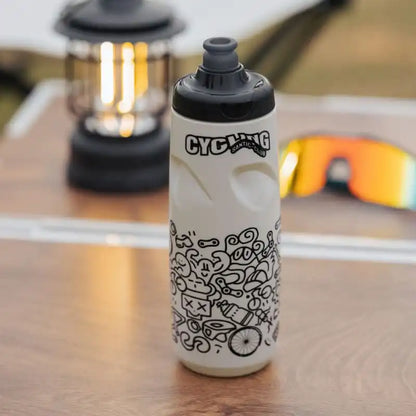 Hvit Santic sykkelflaske med svarte illustrasjoner og Cycling Club-logo på et bord.